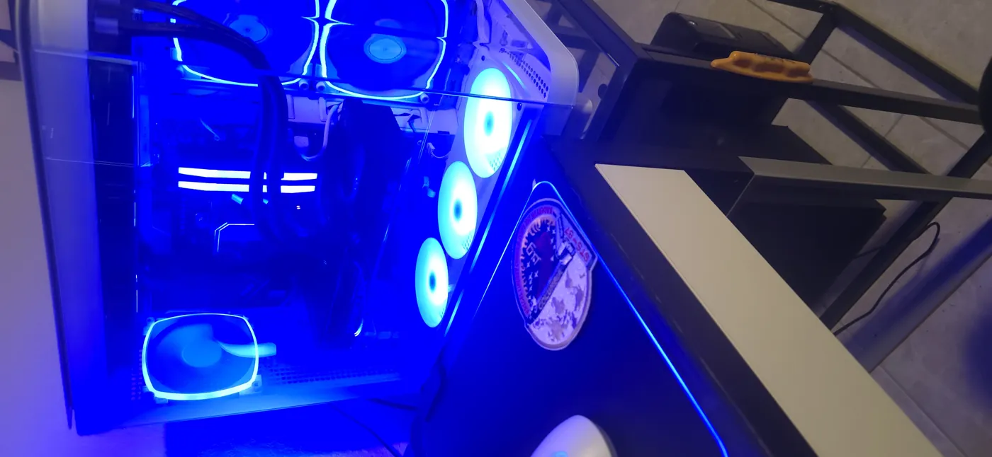 The finished machine running — white case, glass panel, blue RGB fans, the STS-87 mission patch beside it.
